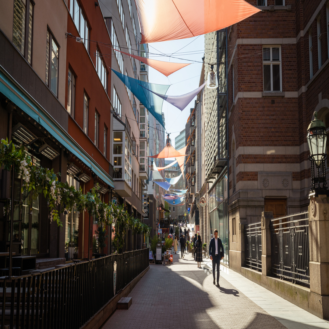 Jakobsbergsgatan inuti MOOD-kvarteret med solsegel och butiker i solljus